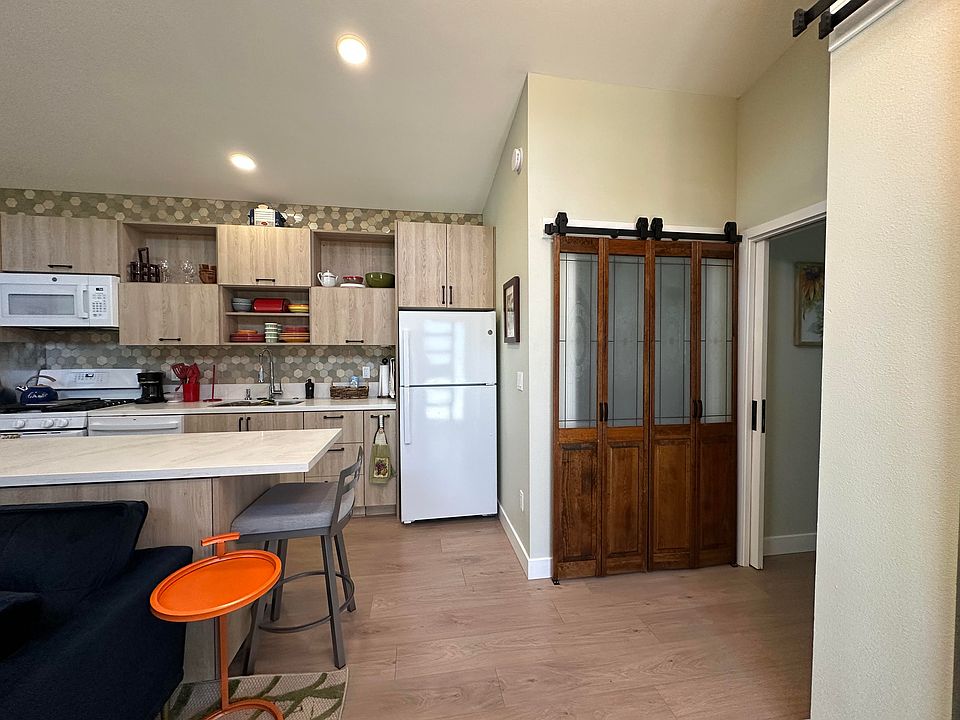 View of kitchen from the front door. Dark wood and glass closet doors have full-sized washer and dryer behind them
