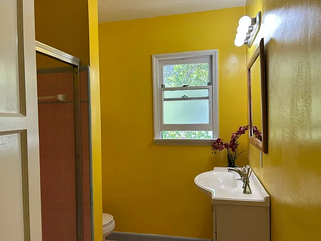 Full bath with custom paint and deluxe lighting, bathroom includes tub/shower with glass enclosure.