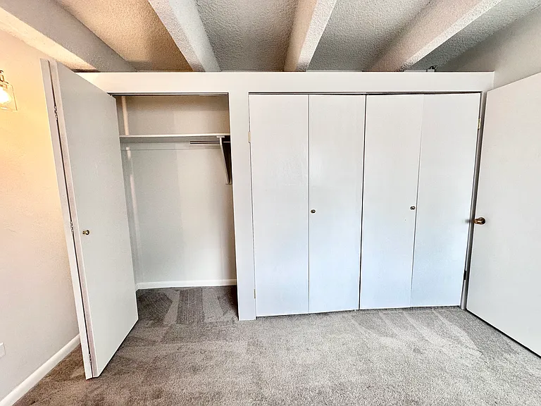 Spacious apartment closet with sliding doors and ample storage space, featuring modern design and cozy carpeted flooring. Spacious apartment closet with sliding doors and ample storage space, featuring modern design and cozy carpeted flooring.