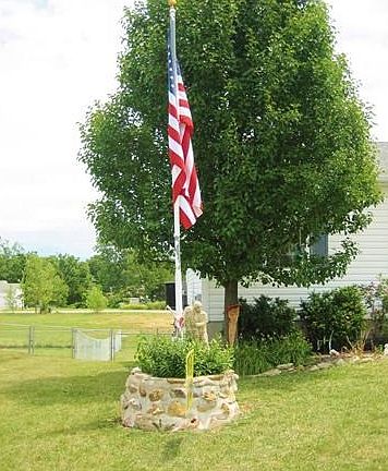 Custom stone wishing well with flag pole graces the front yard.