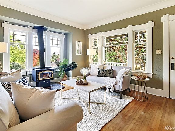 Bright, spacious living room with details intact like wavy windows and hardwood floors . Cozy fireplace completes the room 