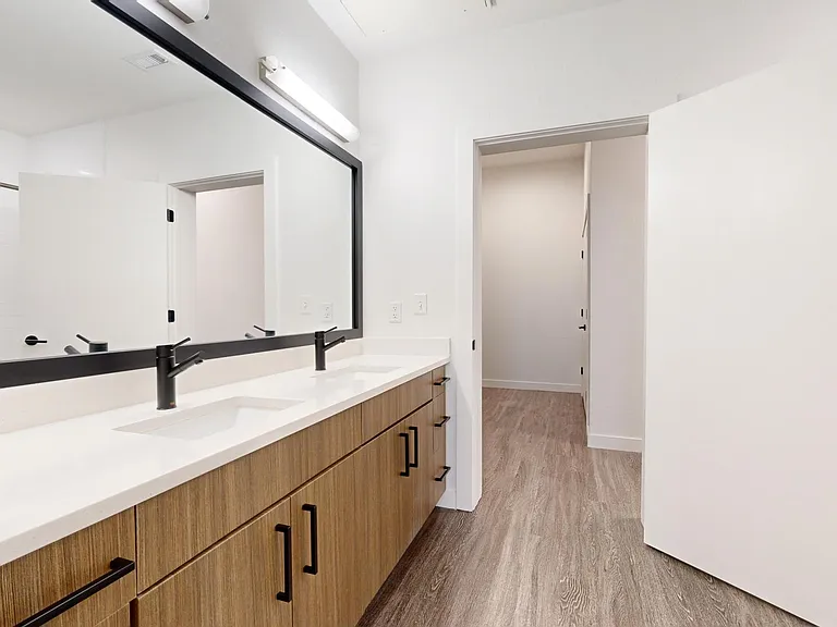 Apartment bathroom with large soaking tub, wood-style flooring and double sinks.