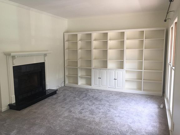 The sunny living room has a gas fireplace and bookshelves.