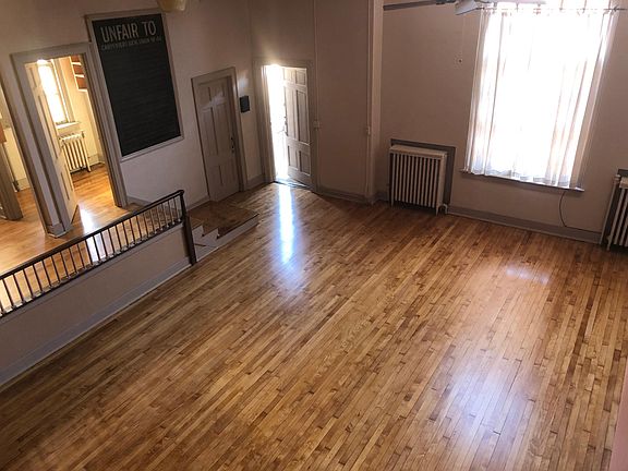 View from loft bedroom overlooking part of living room, kitchen and view of open entrance door.