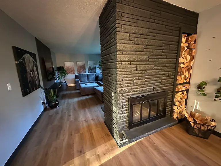 Black accents combined with open wood facing storage create modern design without sacrificing functionality. Wood burning fireplace creates a warm and inviting space.