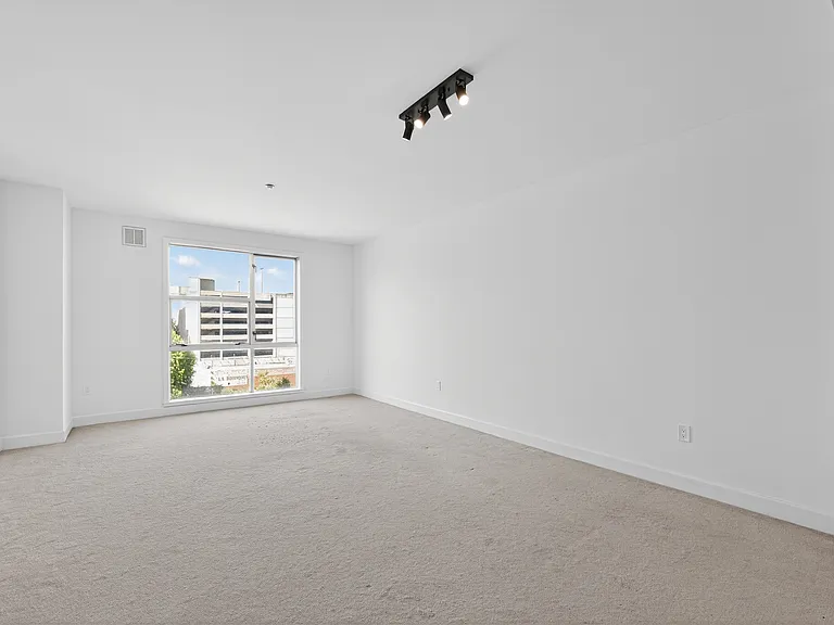 Bright living room with large window, professionally cleaned carpet, fresh white walls, and room for seating, dining, and additional flexible use.
