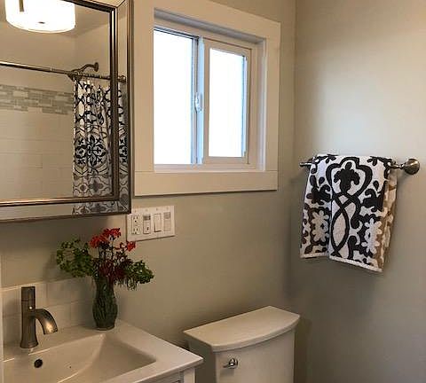 Beautifull bathroom has a soaking tub/shower combination, white subway tile and glass/marble trim, tile floors, white shaker vanity, medicine cabinet for storage, LED lighting.