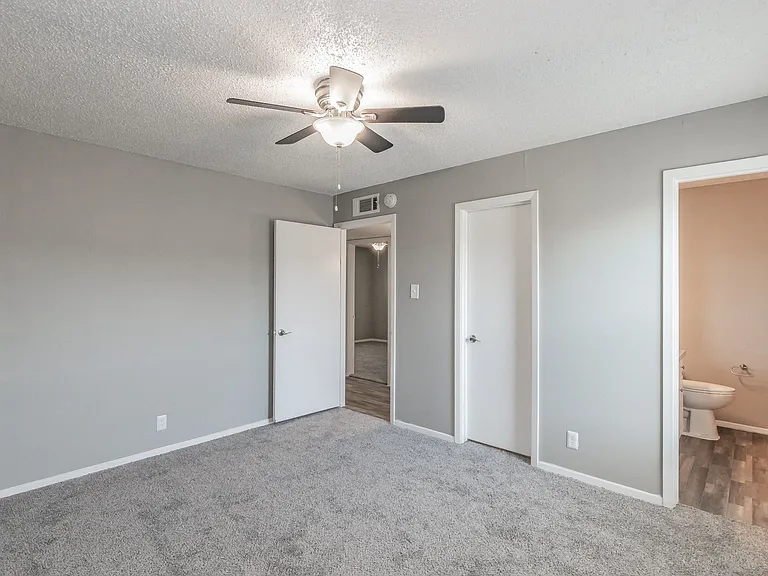 Comfortable bedroom with ceiling fan and soft carpeting