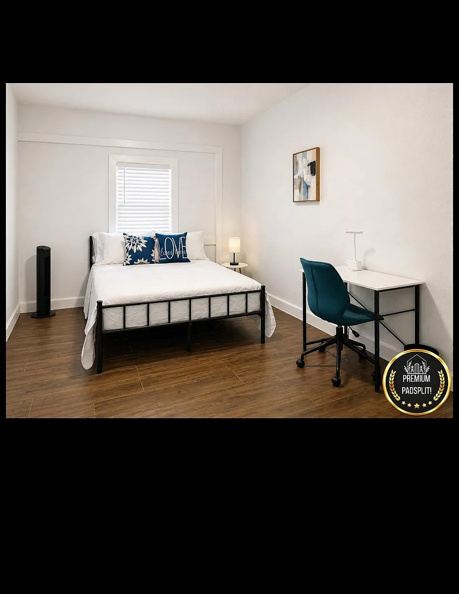 Furnished bedroom with a full bed, dedicated desk workspace, and wood-style flooring plus window blinds for privacy. - Briar Meadow Dr
