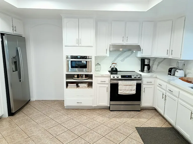 Fully equipped kitchen with cookware, dishware, and eating utensils.