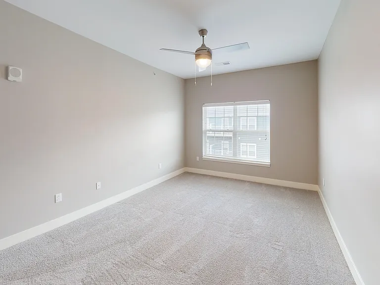 The Kraft floor plan includes a second bedroom with a large window, ceiling fan, and plush carpet. The Kraft floor plan includes a second bedroom with a large window, ceiling fan, and plush carpet.