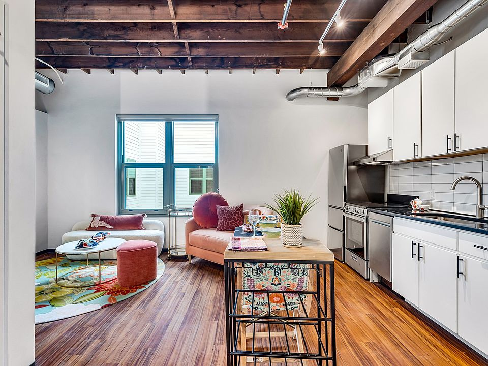 Culinary Elegance: A kitchen adorned with sleek white cabinetry, modern appliances, and rustic wooden beams overhead, combining form and function.