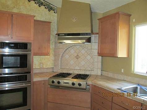 Tiled arch behind propane cooktop is focal point of kitchen.