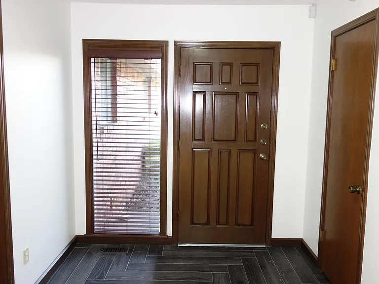 Just inside the front door, window with wood blinds, and large coat closet on the right.
