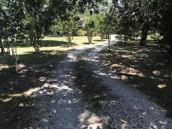The driveway meanders from the entrance through rows of crapemyrtles up to the house.