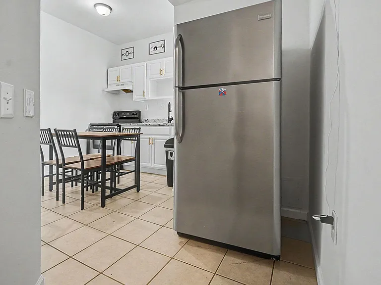 Eat-in kitchen with stainless refrigerator, range, and ample cabinet storage plus a dining table for shared meals.