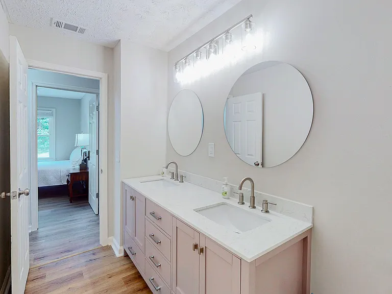 Spacious double-sink vanity with ample drawer storage, large round mirrors, and updated lighting for easy shared routines.