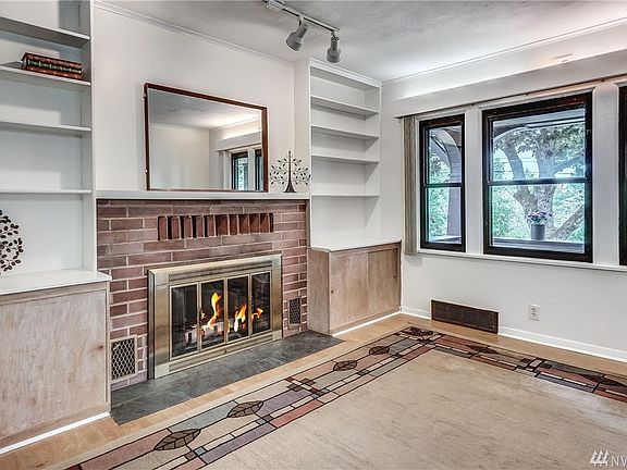 The living room has a warm fireplace banked by built-in shelving and cabinets.