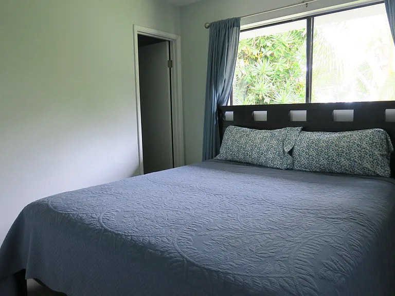 A king bed with a window overlooking a lush yard.