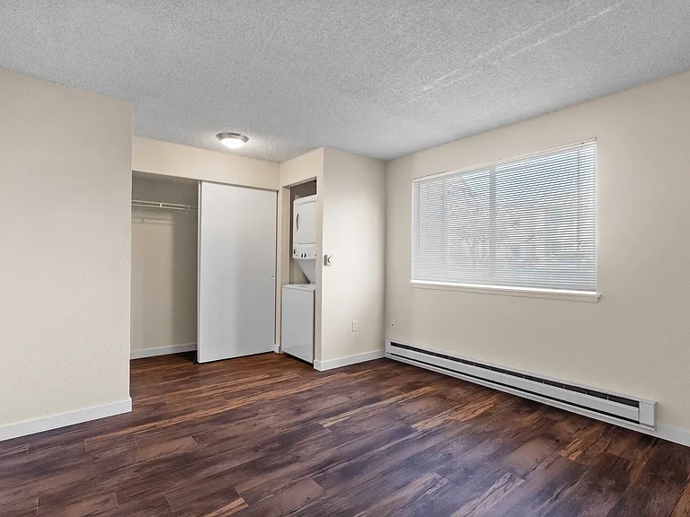 Inviting apartment interior featuring elegant wood flooring, large bright window, and in-unit laundry. Inviting apartment interior featuring elegant wood flooring, large bright window, and in-unit laundry.