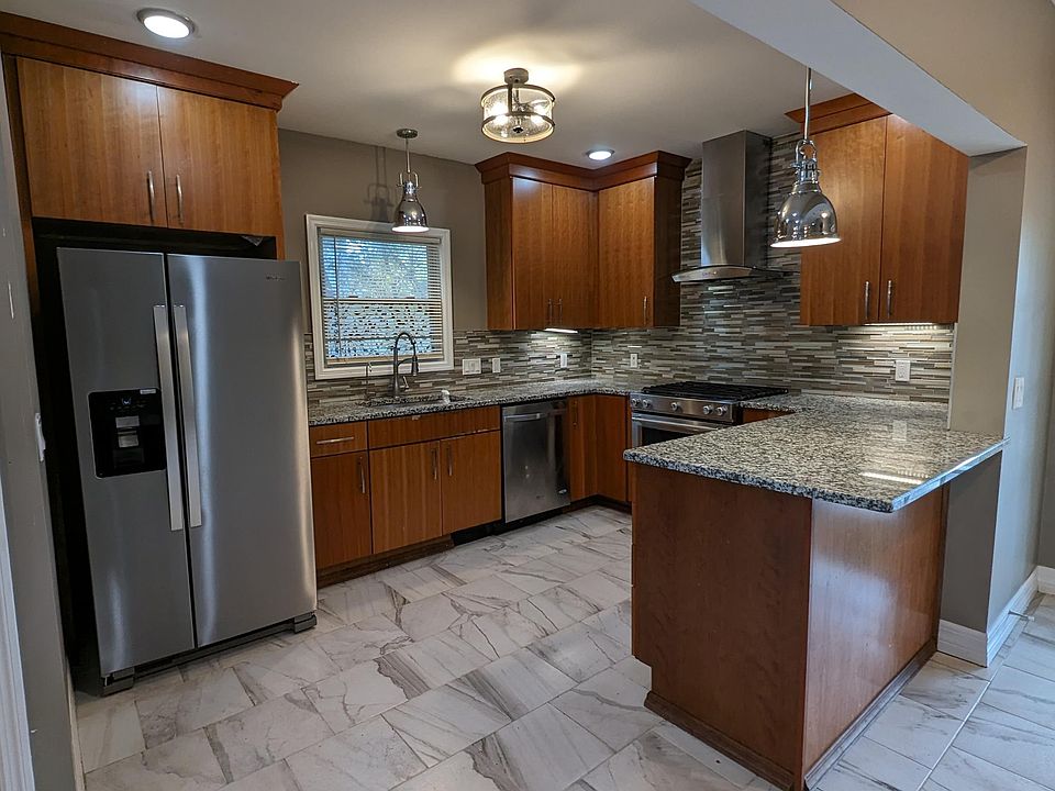 Kitchen with stainless steel appliances, window above sink, and overhang for bar stools