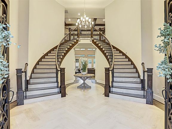 Guests will be impressed as they enter through oversized double wood and glass doors with decorative iron inlay. Step inside to discover gorgeous decorator features throughout like the stunning wood look tile floors, twin grand stair cases with elega