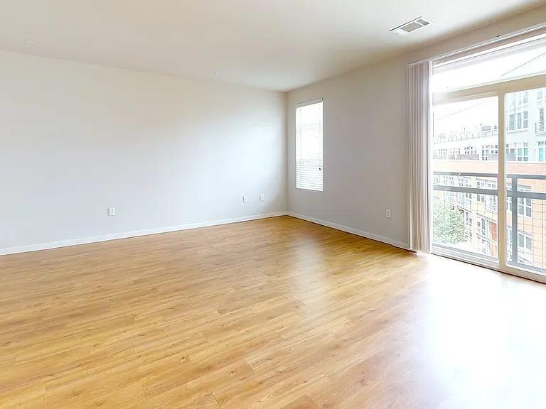 Apartment living room with wood-style flooring and balcony or patio in select homes.