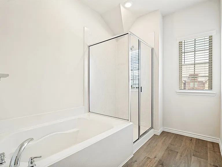 Contemporary bathroom featuring a white soaking tub with chrome fixtures, a glass-enclosed shower, a window with horizontal blinds, recessed lighting, and wood-finish flooring