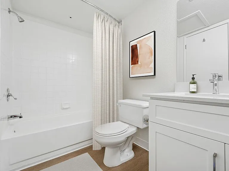 Renovated Package II bath with white cabinetry, quartz countertop, and hard surface flooring