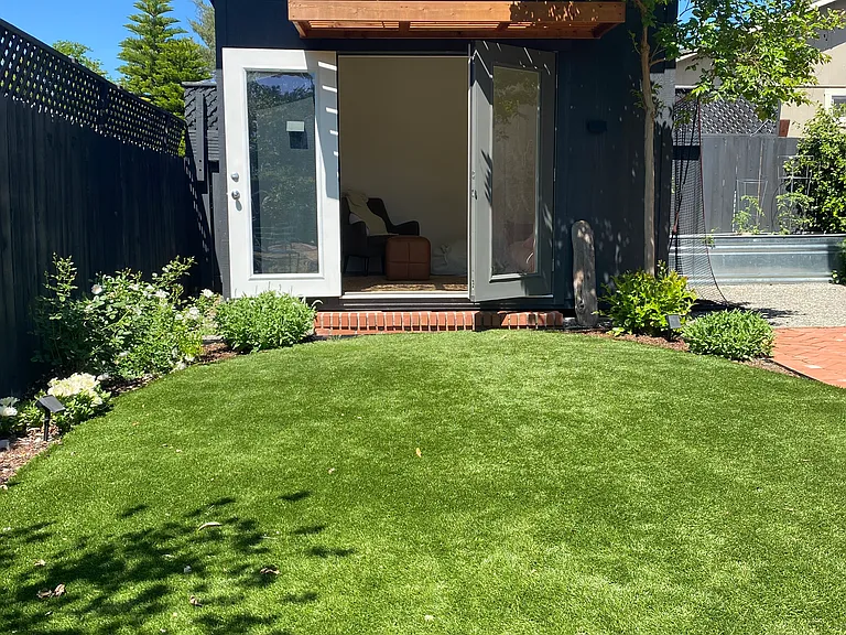 Artificial turf leading up to Studio space with chair, couch, bean bag. Full screen TV, audio system.
