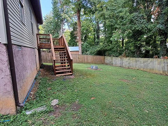 Deck and large fenced yard with fire ring.