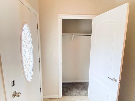 Coat closet next to the front door, neutral tiling