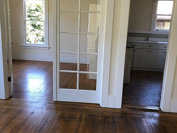 Living room in the foreground, dining room on the left background, kitchen on the right background.