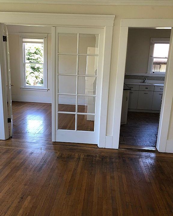 Living room in the foreground, dining room on the left background, kitchen on the right background.