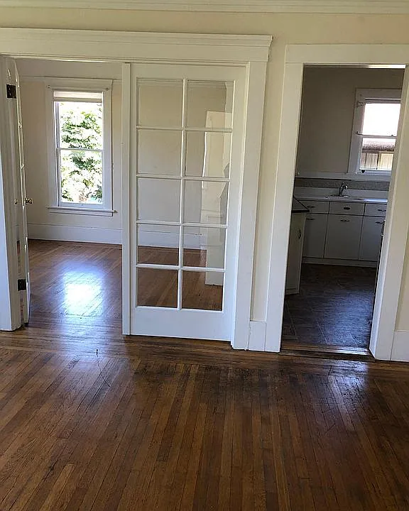 Living room in the foreground, dining room on the left background, kitchen on the right background.