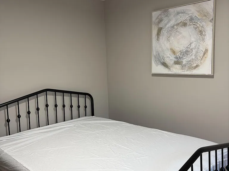 Private bedroom with a metal bed frame, neutral walls, and space for essential furnishings and personal storage.
