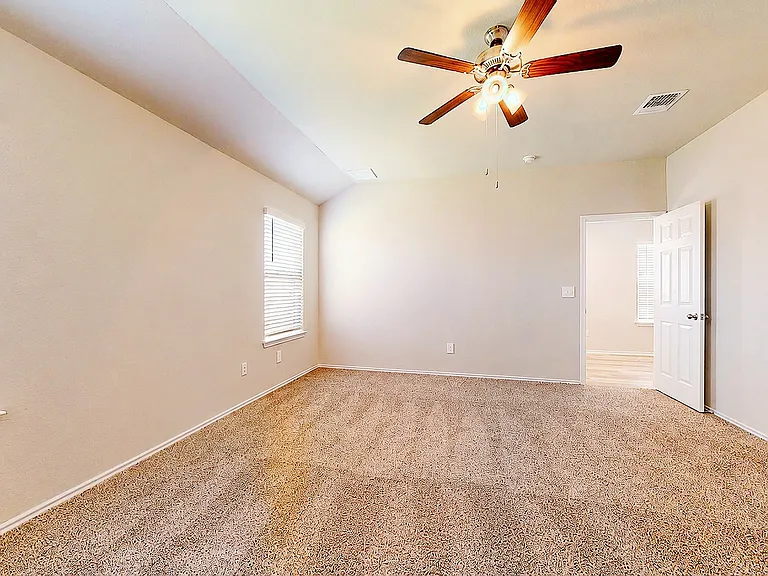 Generously sized primary suite featuring a vaulted ceiling, soft carpet, and dual windows _ a bright, restful retreat with an en-suite bath and walk-in closet just beyond.