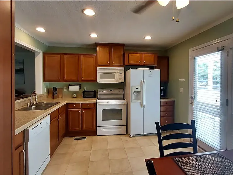 Kitchen with dining table. Appliances include refrigerator, stove, oven, toaster oven, dishwasher, and coffee maker. Plates, utensils and pots and pans are in the cabinets.