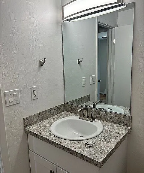 Modern bathroom vanity with sleek granite countertop and elegant mirror, creating a bright and inviting space.