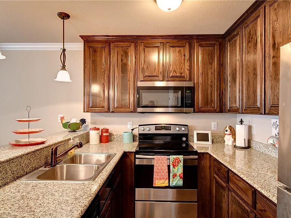 Downstairs kitchen with wood cabinets, granite counter tops, double sink, stove, microwave and refrigerator