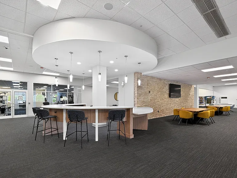 Elegant communal area with modern bar seating, stylish pendant lighting, and a cozy dining space featuring plush mustard chairs.