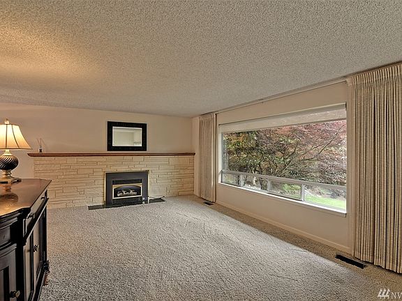 Fireplace with hardwood flooring beneath carpet.