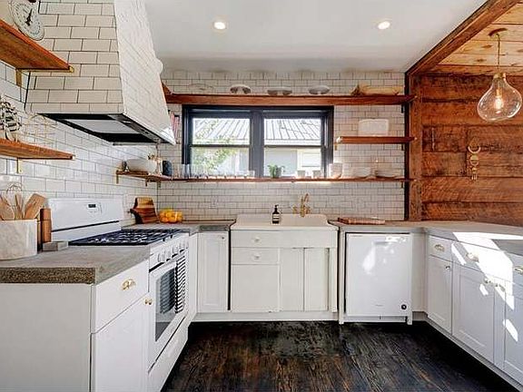 The heart of the home with
incredible natural light! This
kitchen features pendant lighting,
modern subway tile backsplash,
updated concrete countertops,
white cabinetry and updated
appliances with warm hardwood floors.