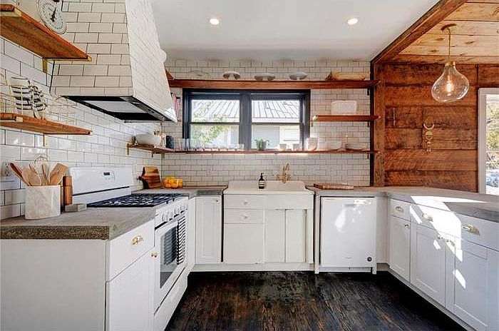 The heart of the home with
incredible natural light! This
kitchen features pendant lighting,
modern subway tile backsplash,
updated concrete countertops,
white cabinetry and updated
appliances with warm hardwood floors.
