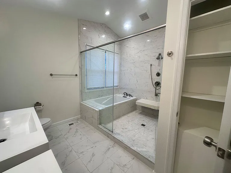 Additional view of the primary bathroom and convenient storage and linen closet.