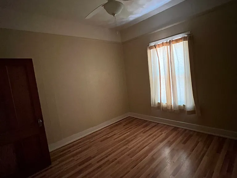 Bedroom with large window and ceiling fan.