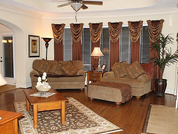 Family room features trayed ceilings, hardwood flooring, and view of pool.