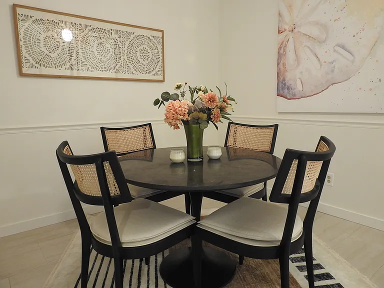Dining room with round marble top table and cane back designer seating.