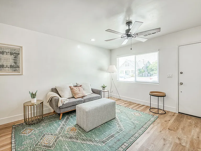Living Room is fully Furnished with Sofas, Area Rug, Dining Table, Scenic Arts on the Wall and Decor Tables.