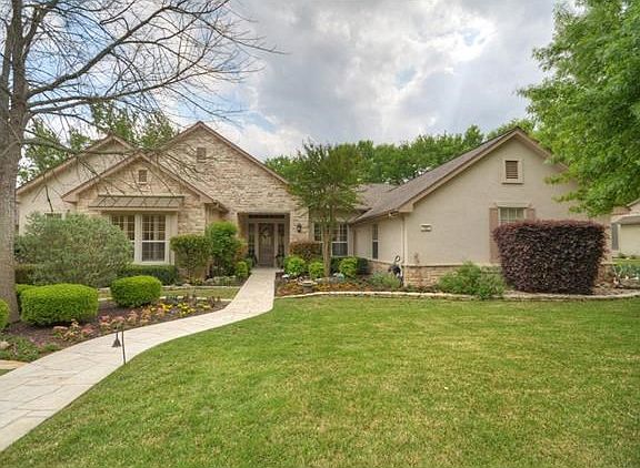 Curvy, stone planting beds and a Side-Entry Garage form a lovely Front elevation at this Sun City Texas Rio Grande Estate home.
